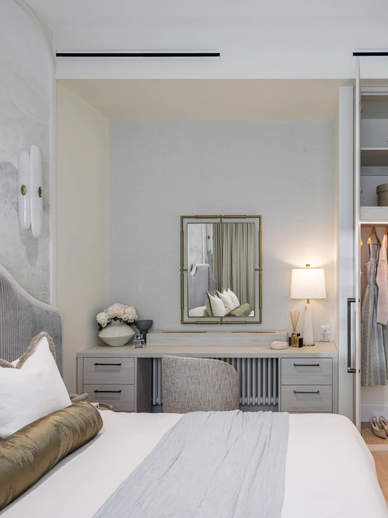 Fitted dressing table, drawers and lit wardrobe in a bedroom